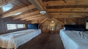 Un dormitorio acogedor en el desván, con dos camas, vigas de madera y techo inclinado.