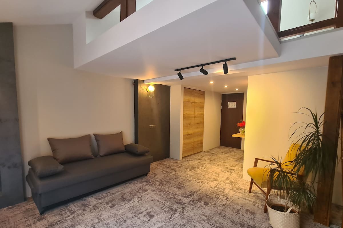 A modern living room with a grey sofa, a wooden door, and a yellow chair.