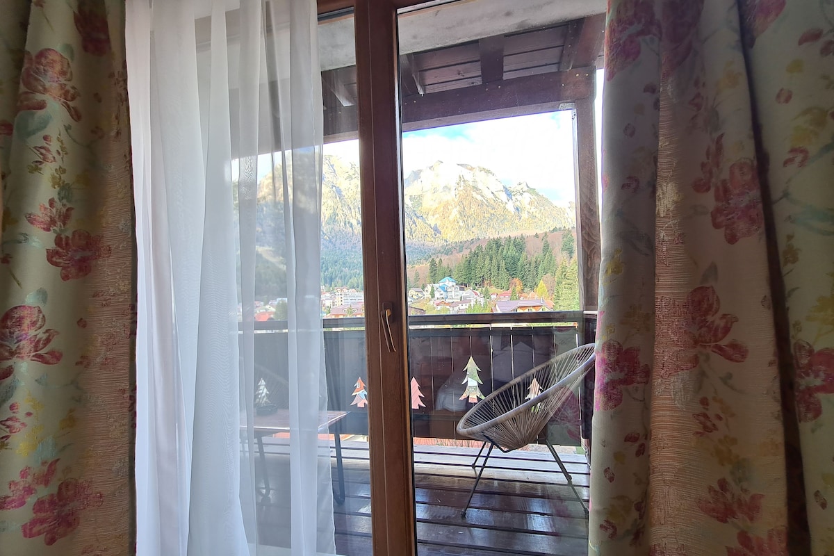 Habitación con vistas a montañas y un balcón con una silla.