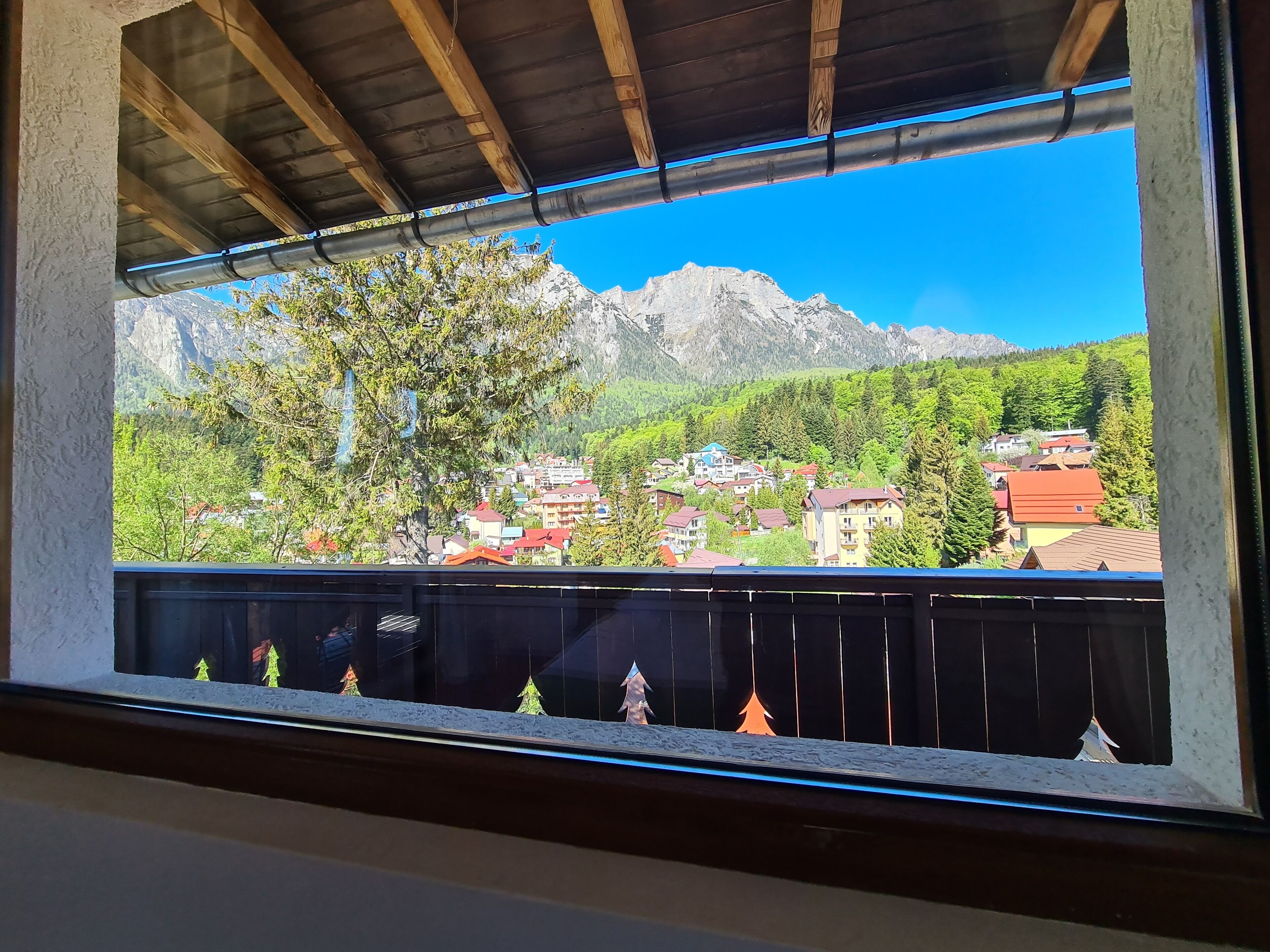 Uma varanda com vista para uma cordilheira e uma aldeia lá embaixo.