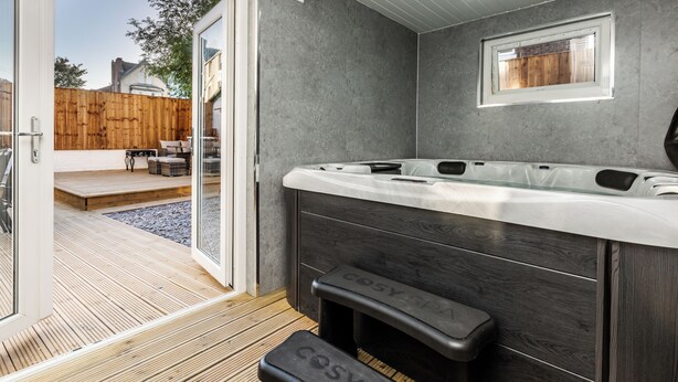 A modern bathroom with a large bathtub, a bench, and a window.