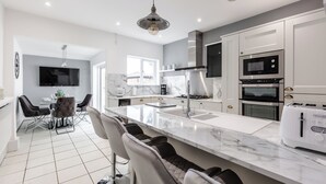 A modern kitchen with a large island, built-in appliances, and a dining area with bar stools.