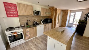 A modern kitchen with wooden cabinets, a built-in microwave, a stove, and a dishwasher. - Large, comfortable villa in the Cévennes, mountains, lakes and rivers. Pets welcome! (concoules)