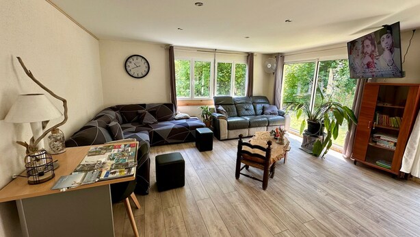A spacious living room with a sofa, armchair, and a small table with a lamp. - Large, comfortable villa in the Cévennes, mountains, lakes and rivers. Pets welcome! (concoules)
