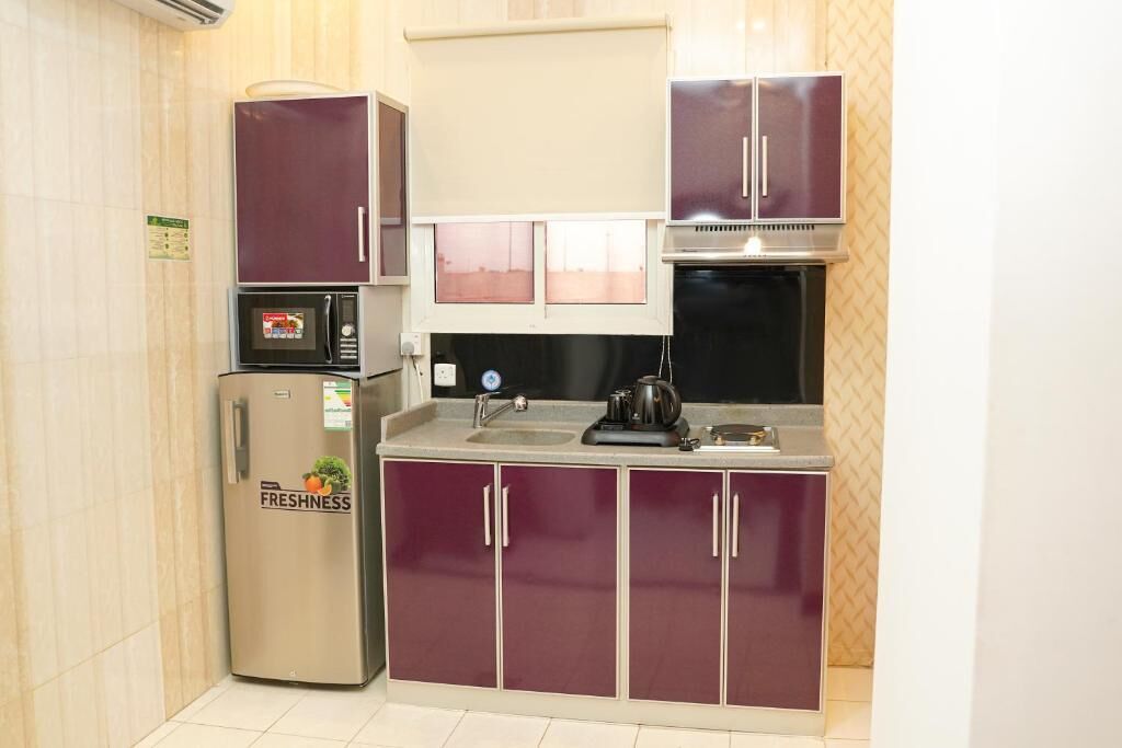 Una cocina pequeña equipada con refrigerador, microondas y estufa.