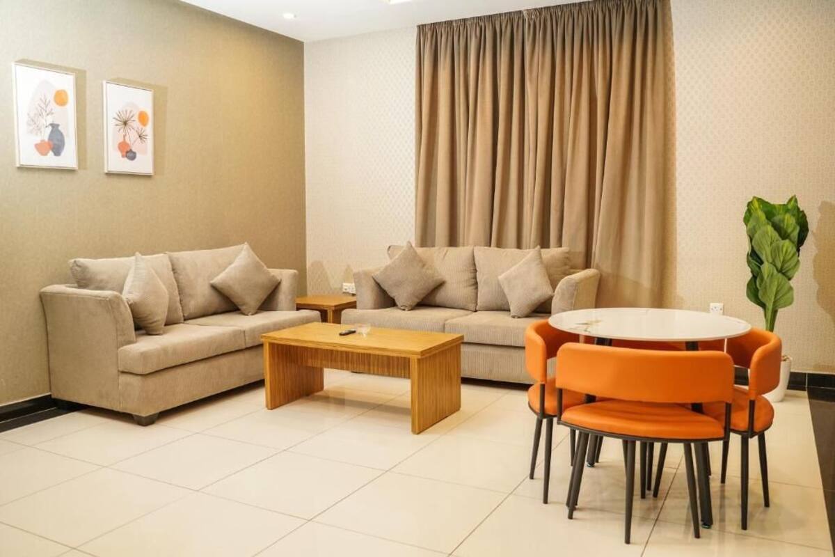 A living room with a beige sofa, a wooden coffee table, and orange chairs.