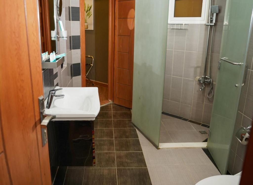 Een badkamer met een wit wastafelmeubel, een douchecabine van glas en een toilet.