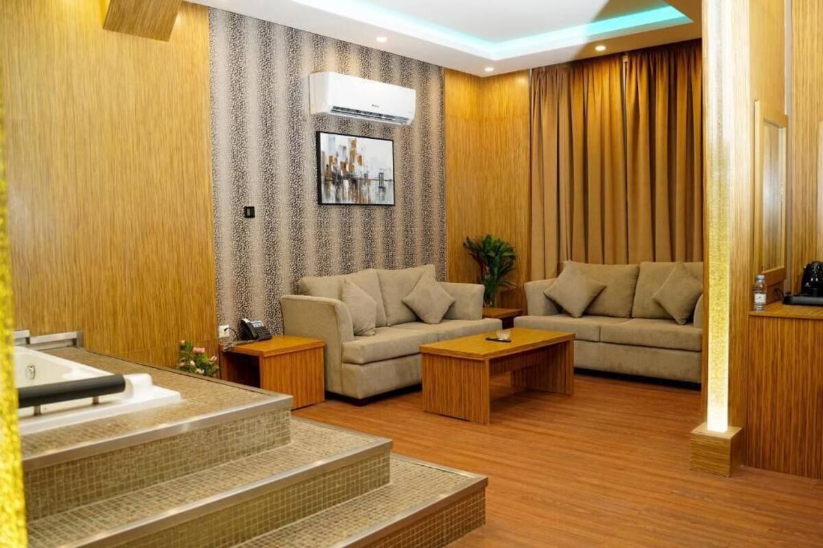A modern living room with two sofas, a coffee table, and a small kitchen area.