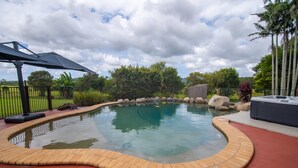 A swimming pool with a curved edge, surrounded by a brick deck, and a hot tub to the right. - The Old Sugar Mill Country Escape in Paradise (Bridges)
