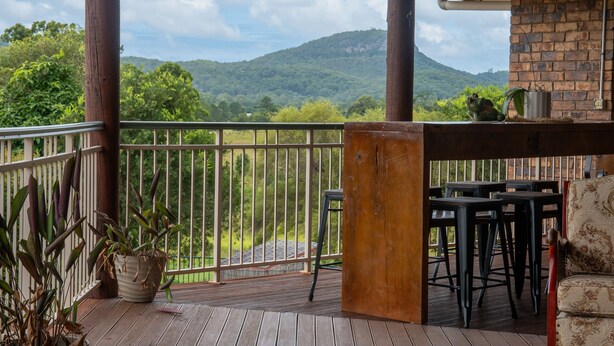 A wooden deck with a railing, a table, and chairs. - The Old Sugar Mill Country Escape in Paradise (Bridges)