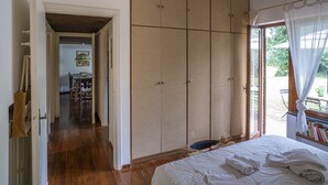 A bedroom with a bed, a wardrobe, and a view of the outdoors.