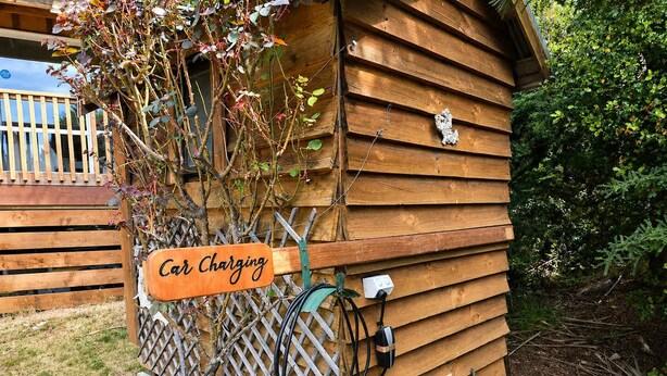 Eine Holzhütte mit angebrachtem Ladestation für Autos.