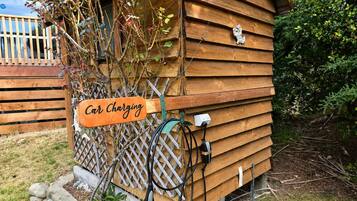 A wooden cabin with a car charging station attached to its exterior.
