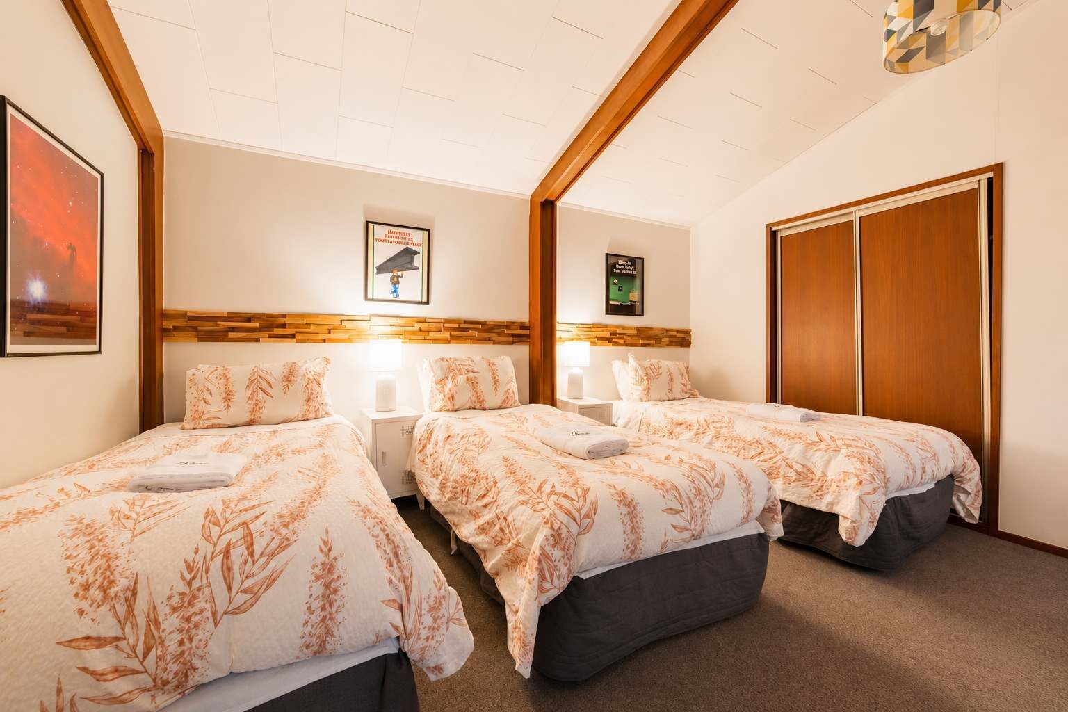 Une chambre d’hôtel avec deux lits, une tête de lit en bois, une armoire et un tableau encadré au mur.