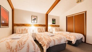 Ein Hotelzimmer mit zwei Betten, einem Holz-Kopfteil, einem Kleiderschrank und einem gerahmten Bild an der Wand.