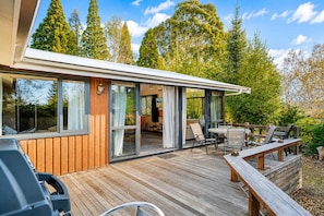 A modern house with a deck, large windows, and a patio area.