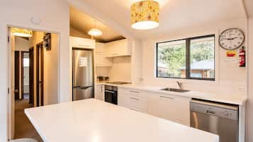 A modern kitchen with a central island, stainless steel appliances, and a window providing a view.