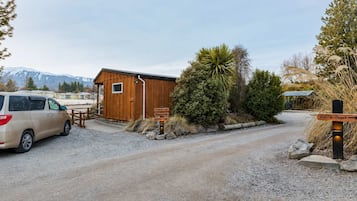 A gravel driveway leading to a wooden cabin with a van parked nearby.