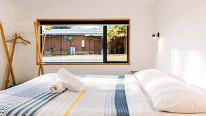 A hotel room with a bed, a window, and a view of the outside.