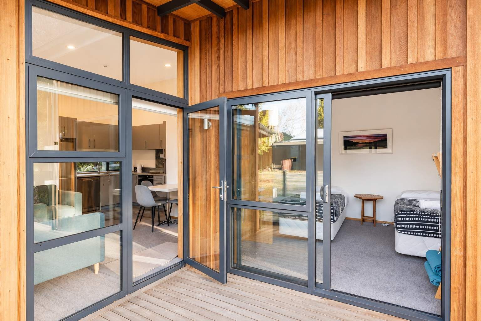 A modern interior with a wooden ceiling, a dining area with a table and chairs, and a cozy seating area with a sofa and a small table.
