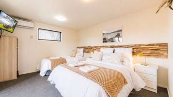 A hotel room with two beds, a TV, a wooden headboard, a bedside table with a lamp, and a picture on the wall.