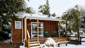 A wooden cabin with a covered porch, a sliding glass door, and two chairs outside. - Polaris | Lake Tekapo | Near Church + Balcony (Lake Tekapo)