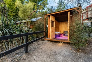 Une petite cabane en bois avec un lit simple, une table et un banc.