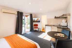 Een hotelkamer met een bed, een eettafel, een kitchenette en een televisie.