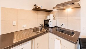 A kitchenette with a stainless steel sink, a microwave, a toaster, and a built-in range hood. - Polaris | Lake Tekapo | Near Church + Balcony (Lake Tekapo)