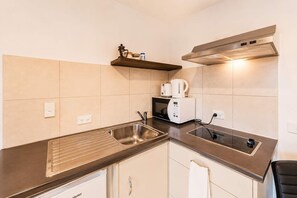 Een kitchenette met een roestvrijstalen spoelbak, een magnetron, een broodrooster en een inbouw afzuigkap.