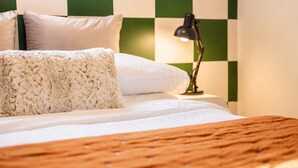 A bed with a wooden headboard, white bedding, and a green and white checkered wall.