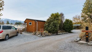 A gravel driveway leading to a wooden cabin with a van parked nearby. - Polaris | Lake Tekapo | Near Church + Balcony (Lake Tekapo)