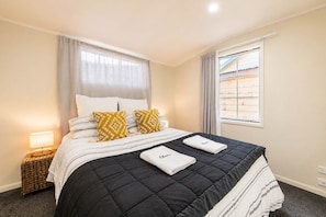 Habitación de hotel con cama, dos almohadas, lámpara de noche, ventana y vista al exterior.