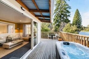 A deck with a hot tub, outdoor seating, and a view of trees. - Milkyway Lodge | Hot Tub + Scenic Views (Lake Tekapo)