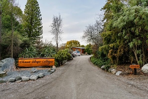 A gravel driveway leading to a wooden building with a sign reading 'Ohana Tekapo Cottages.' - Milkyway Lodge | Hot Tub + Scenic Views (Lake Tekapo)