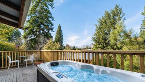A hot tub on a wooden deck with a view of trees and mountains. - Milkyway Lodge | Hot Tub + Scenic Views (Lake Tekapo)