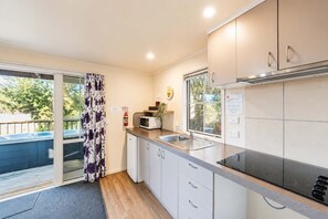 A compact kitchen with a microwave, sink, and cabinets. - Milkyway Lodge | Hot Tub + Scenic Views (Lake Tekapo)