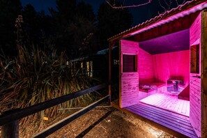 A wooden sauna with a bench and a table, surrounded by a wooden fence and vegetation. - Little Dipper | 2BR | Near Lake + Church (Lake Tekapo)