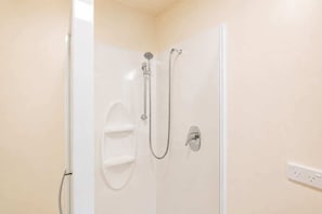 A shower with a handheld showerhead and a wall-mounted faucet.