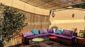 A cozy outdoor seating area with a cushioned sofa, a small round table, and a potted plant. - Maison de Charme a Deux pas de la Méditerranée (Toulon)