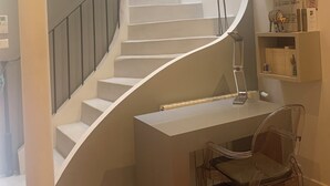 A modern interior with a spiral staircase, a desk with a chair, and built-in shelving with books and decorative items. - Maison de Charme a Deux pas de la Méditerranée (Toulon)