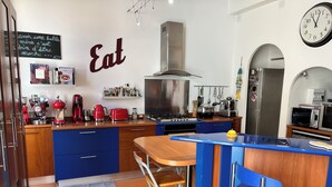 A modern kitchen with blue cabinets, a gas stove, red appliances, and a chalkboard sign. - Maison de Charme a Deux pas de la Méditerranée (Toulon)