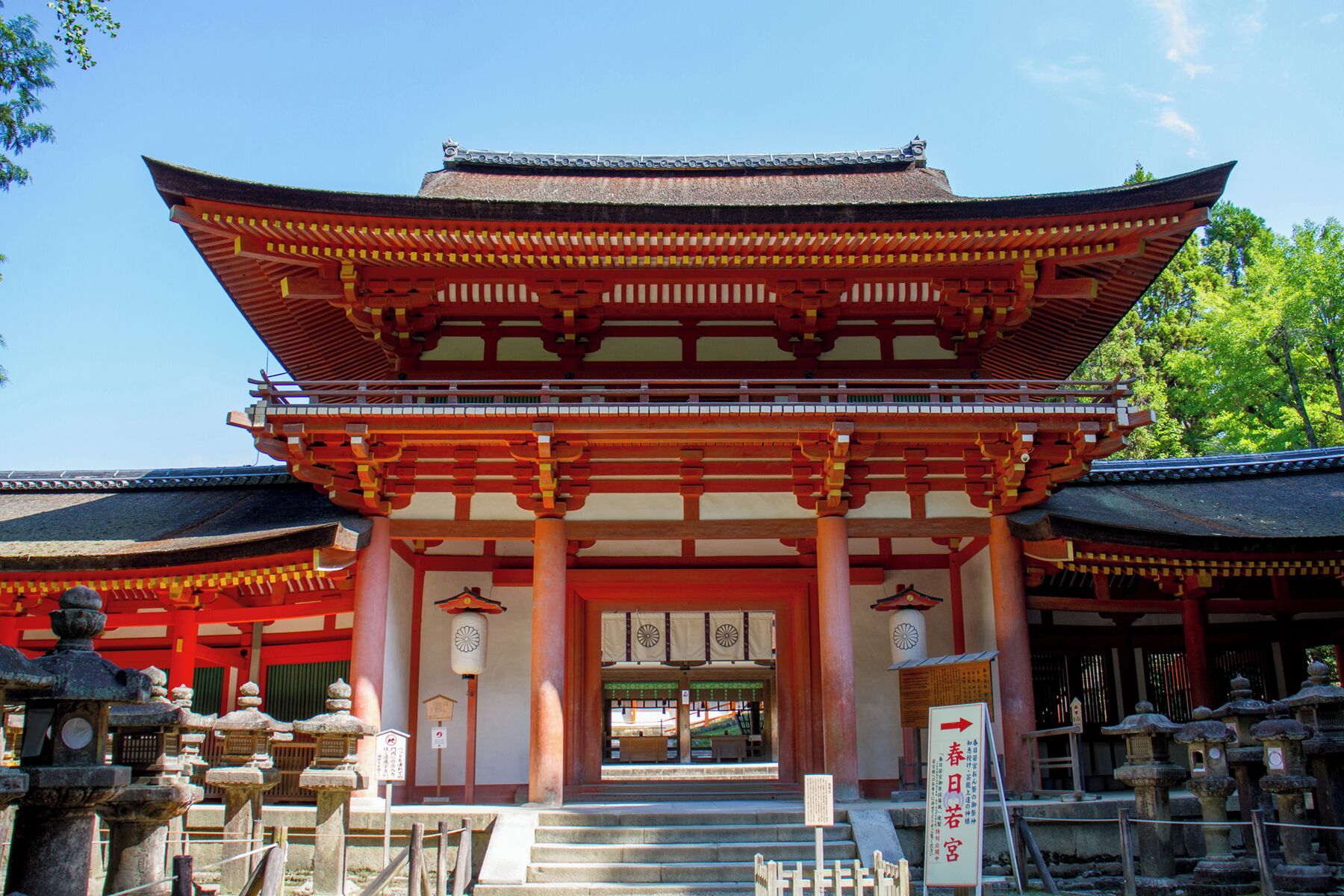 A traditional Japanese building with a multi-tiered roof, wooden pillars, and a stone lantern in the foreground.