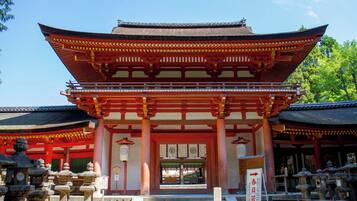 Un edificio japonés tradicional con tejado de varios niveles, columnas de madera y un farolillo de piedra en primer plano.