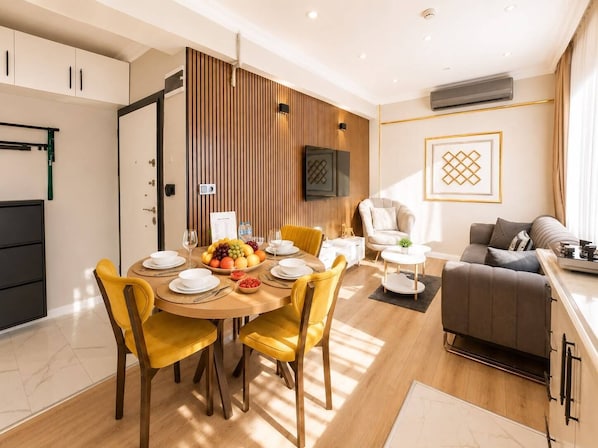 A modern living room with a dining area, a sofa, and a TV mounted on the wall. - Casa Florya Otel (Istanbul)