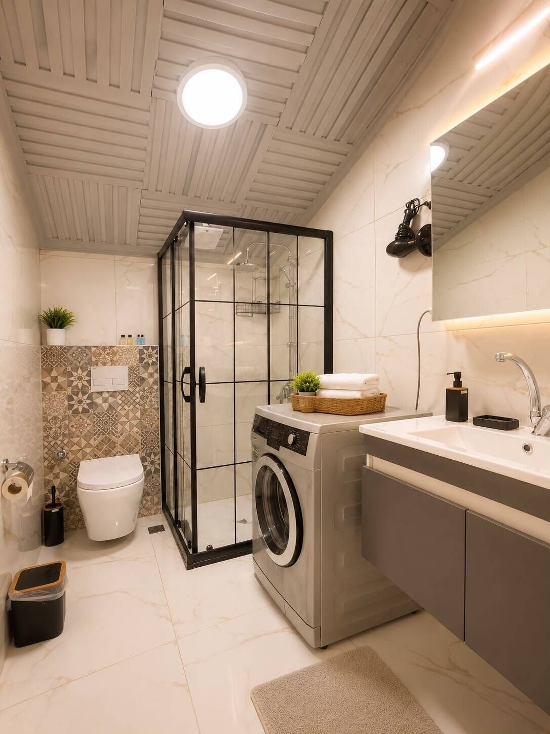 Un baño moderno con cabina de ducha de vidrio, lavadora integrada, lavamanos con espejo y un inodoro.