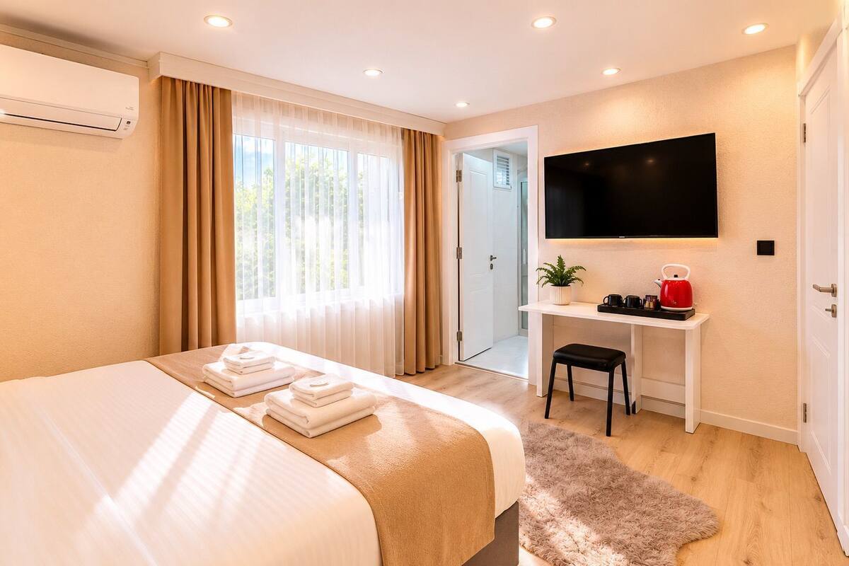 A modern hotel room with a bed, a desk, a TV, and a door.