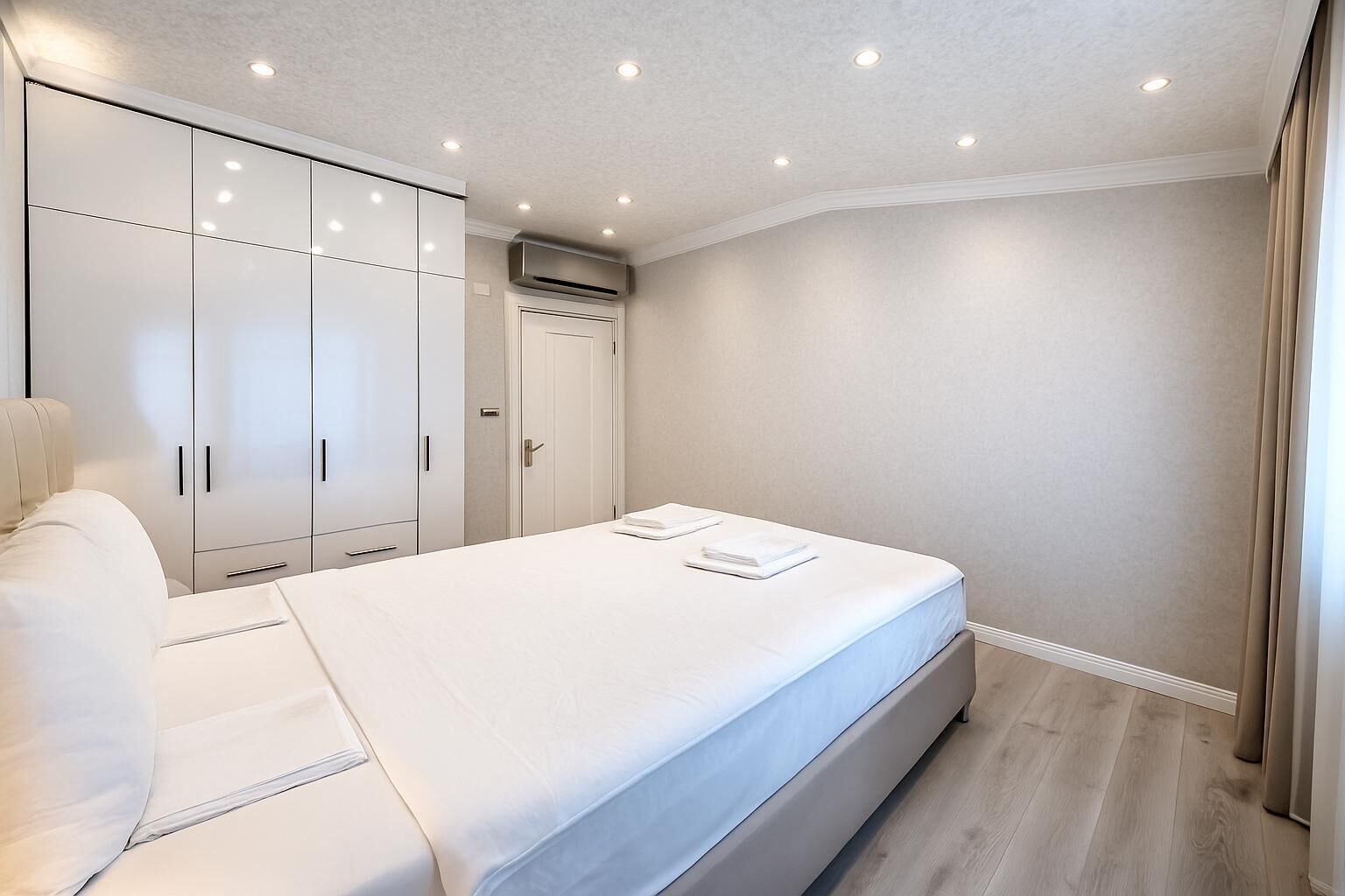 A modern bedroom with a bed, white wardrobe, and a ceiling with recessed lighting.
