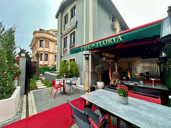 Un café llamado Cafe de Florya con terraza y toldo rojo.