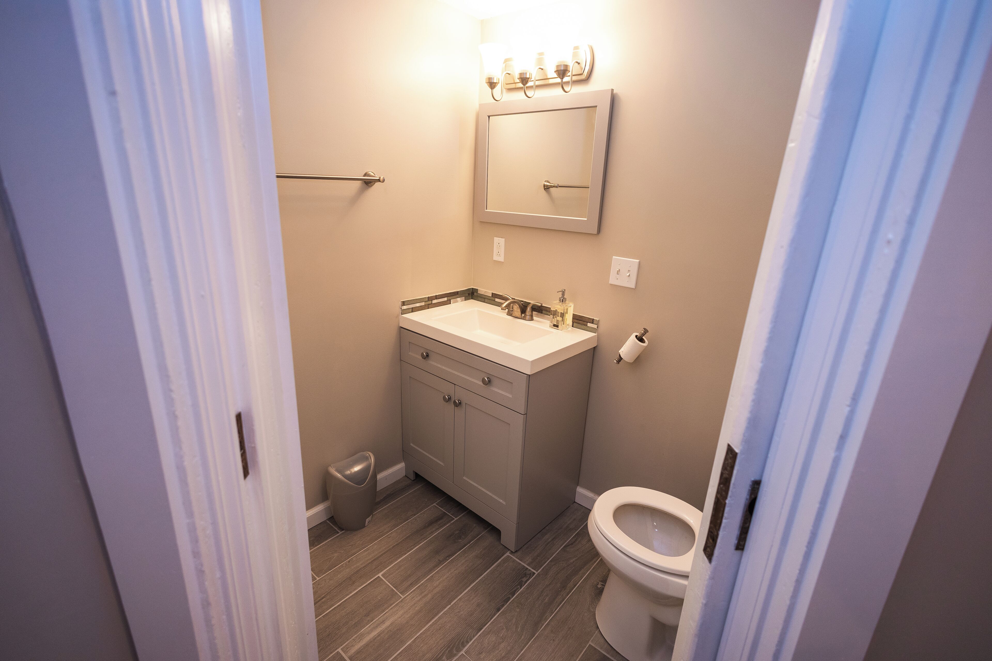 A compact bathroom with a white sink, a mirror, and a toilet.